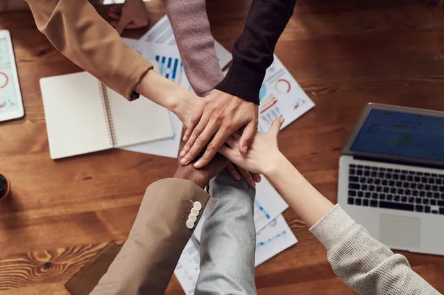 Four people placing their hands together as a sign of collaboration